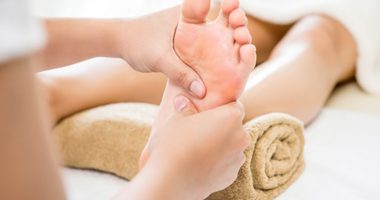 Professional therapist giving relaxing traditional thai reflexology foot massage to a woman in spa