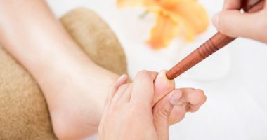 Therapist giving traditional thai foot massage with stick to a woman in spa